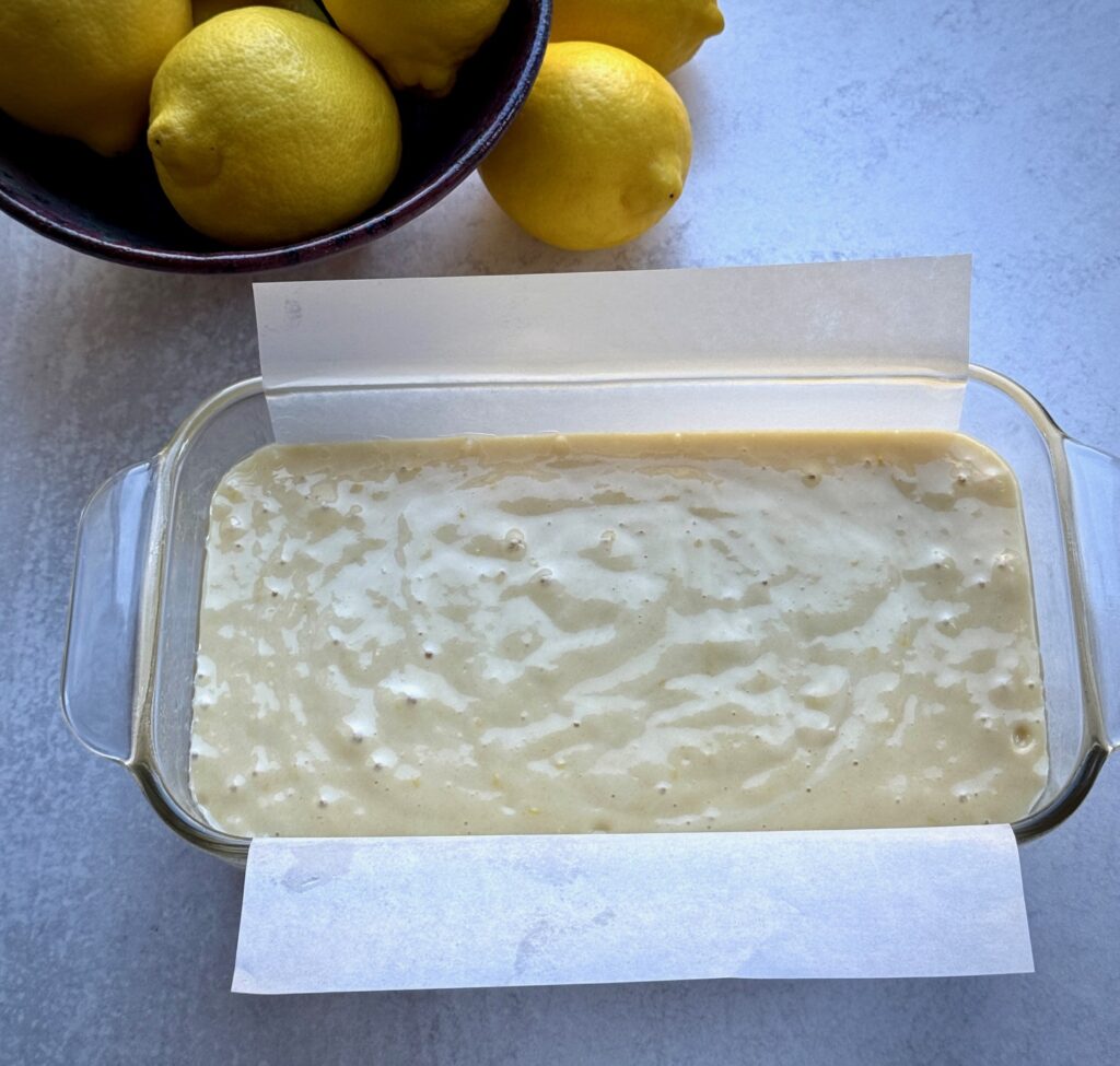 lemon cake batter in loaf pan lined with parchment