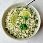 a bowl of cilantro rice with spoon and garnish