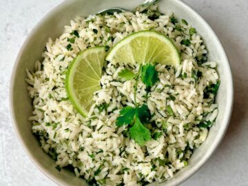 a bowl of cilantro rice with spoon and garnish