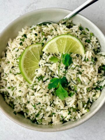 a bowl of cilantro rice with spoon and garnish