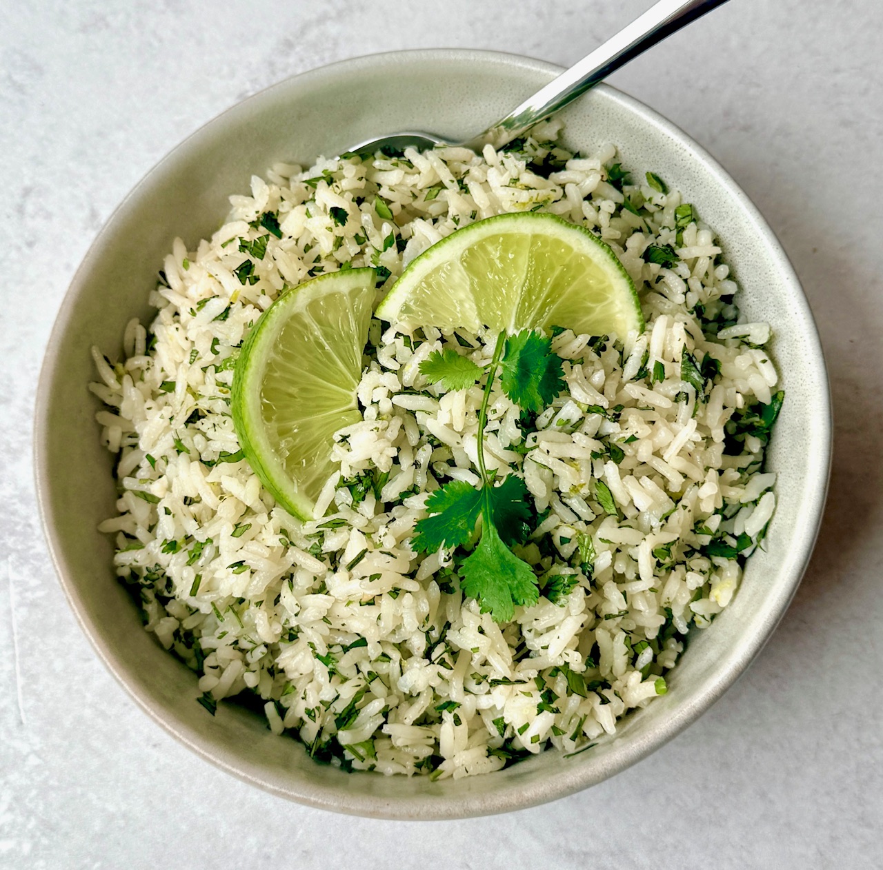a bowl of cilantro rice with spoon and garnish