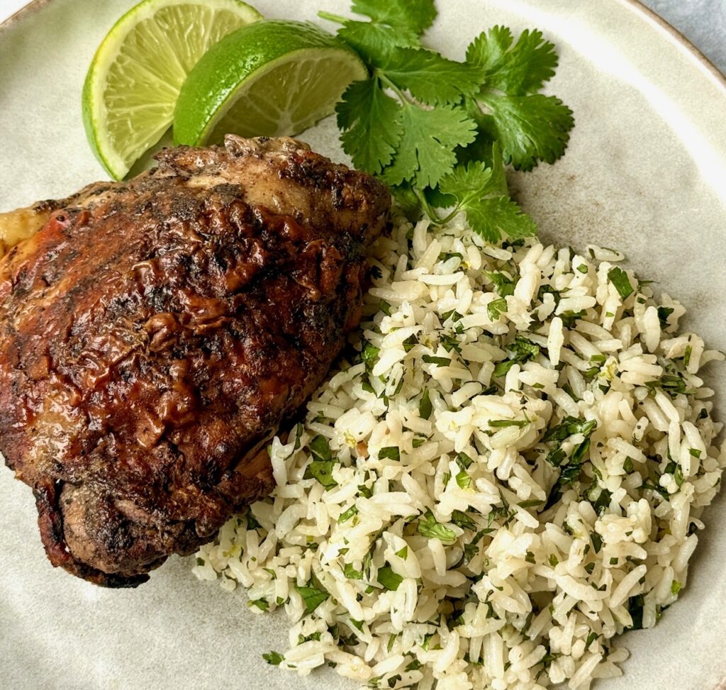 jerk chicken and cilantro rice on a plate with garnish