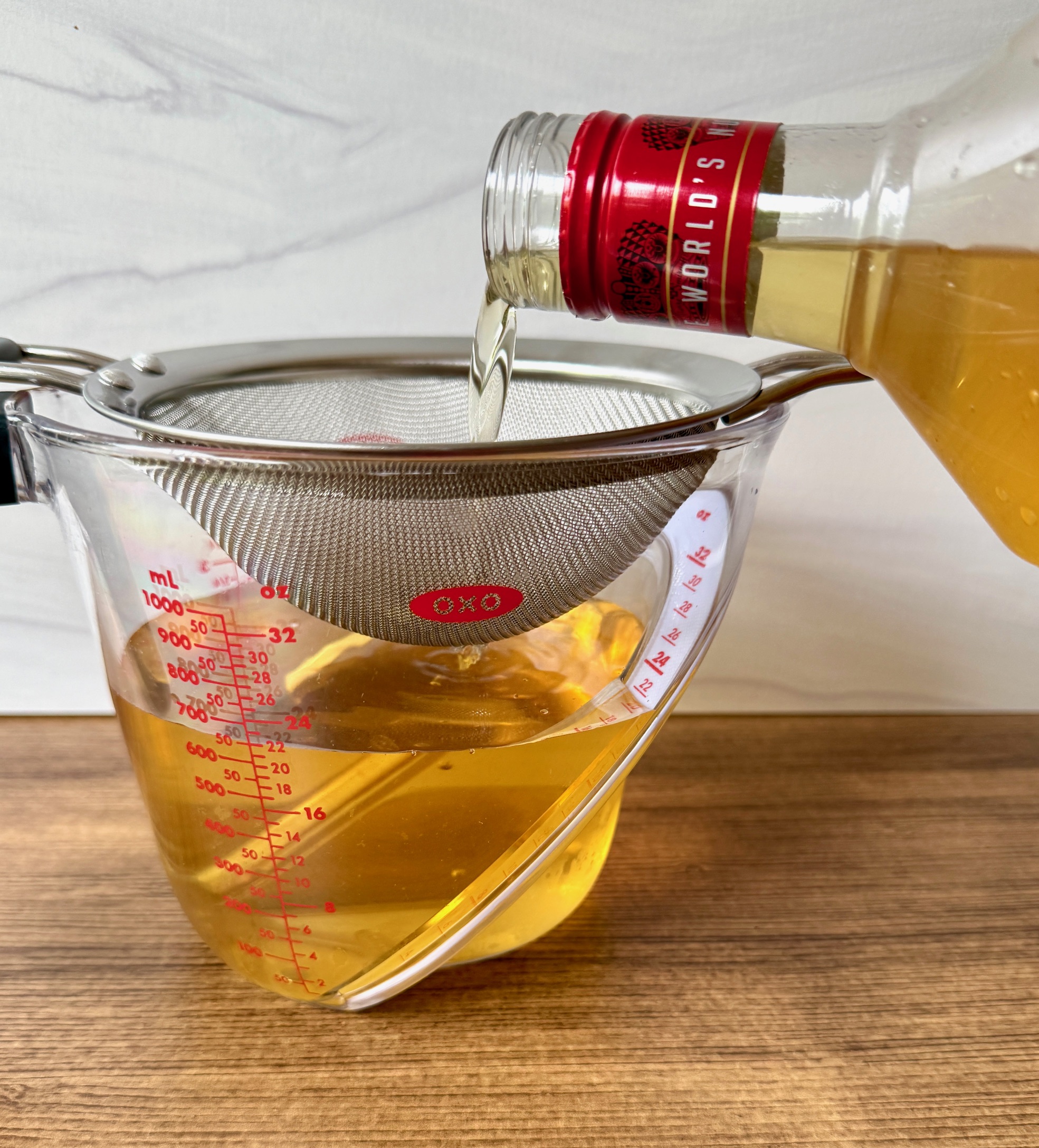 straining lemon vodka in measuring cup