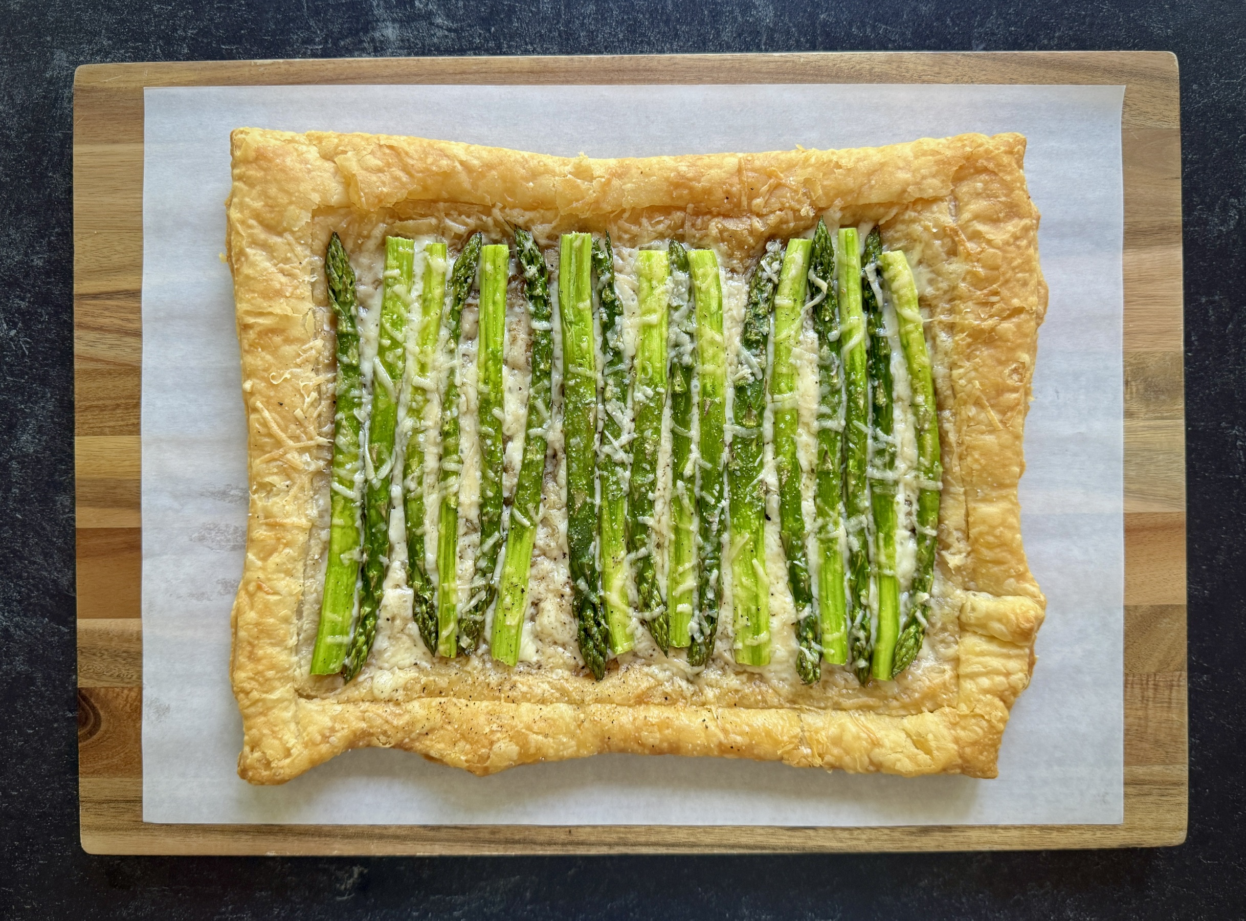 black background and asparagus tart on a cutting board